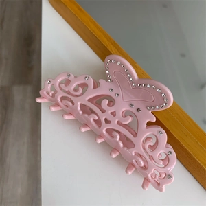Detail shot of a pink acetate heart hair claw clip with rhinestones and hollow design