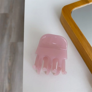 Close-up of pink jelly hair claw clip with transparent acetate finish on white surface
