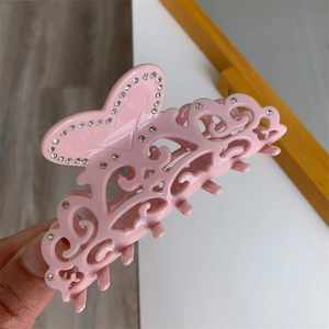 Detail of pink hollow hair claw clip with butterfly design and inlaid rhinestones