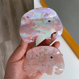 Unique elephant-shaped acetate hair claw clip with colorful mosaic pattern in hand