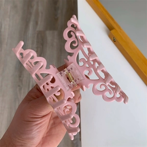 Detail shot of a large light pink hollow-out hair claw clip with intricate patterns