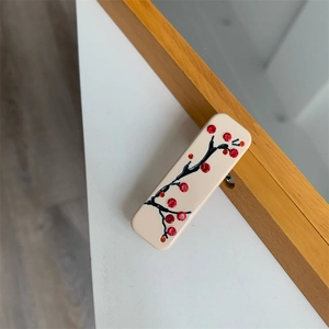 Détail d'une pince à cheveux rectangulaire avec branches de prunier et strass rouges