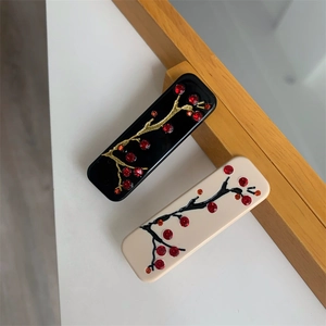 Détail de pinces à cheveux de style chinois avec motifs de prunier et strass rouges
