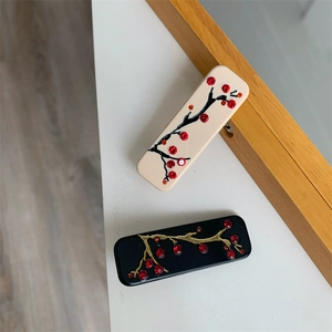 Détail de deux pinces à cheveux rectangulaires avec fleurs de prunier en strass et motifs