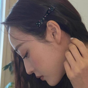 Side view of model wearing a black bow hair clip adorned with colorful rhinestones