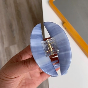 Close-up of elephant shaped acetate hair claw clip with blue marble pattern and metal spring