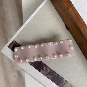 Détail d'une barrette rectangulaire rose tendre ornée de perles élégantes polies