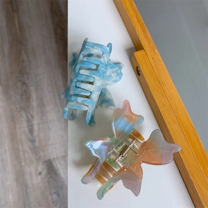 Détail des pinces à cheveux colorées en acétate avec motif marbré et design papillon