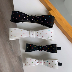 Close-up of black and white bow hair clips featuring colorful rhinestone accents