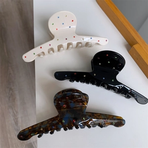 Détail de trois pinces à cheveux en acétate avec strass colorés en crème, noir et écaille