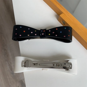 Detail view of acetate bow hair clips featuring colorful rhinestones and spring metal grip
