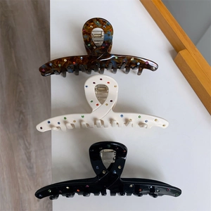 Détail de trois pinces à cheveux en acétate noir, crème et écaille avec des strass colorés
