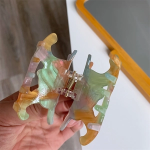 Détail d'une pince à cheveux en acétate coloré avec motif marbré et ressort transparent