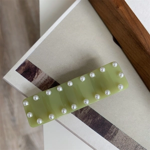 Détail d'une pince à cheveux rectangulaire vert matcha avec d'élégantes perles de bordure