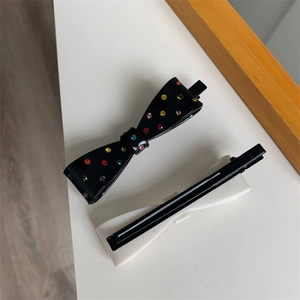 Detail view of acetate bow hair clips with colorful rhinestones on a white surface