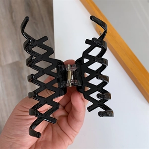 Dettaglio di un grande fermaglio per capelli nero traforato con molla in metallo dorato
