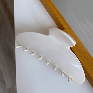 Detail view of a large cream acetate shark clip with smooth texture and sturdy grip teeth