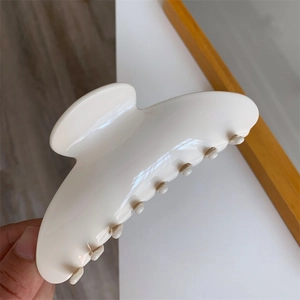 Close-up of a large cream-colored acetate hair claw clip held in hand for size display