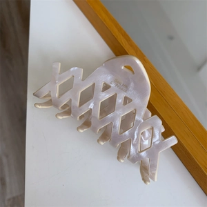 Dettaglio molletta per capelli in acetato rosa con trama a rete e scritta Barrette La France