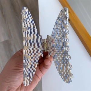 Detail showing butterfly hair claw clip with blue and white checkerboard pattern acetate