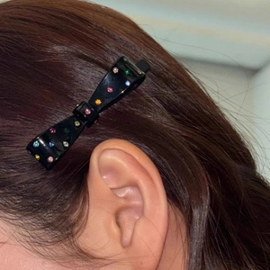 Elegant black bow hair clip with colorful crystals worn on side hair for women