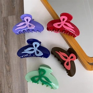 Détail de cinq pinces à cheveux à nœuds colorés en violet rouge bleu marron et vert