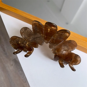 Detail view of large acetate flower hair claw in translucent brown with grid texture
