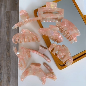 Macro detail of elegant pink marble acetate hair claws with premium pearl embellishments