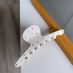 Détail d'une pince à cheveux en acétate crème ornée de strass colorés étincelants