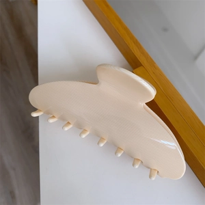 Macro detail of creamy white large acetate claw clip with fine horizontal textures