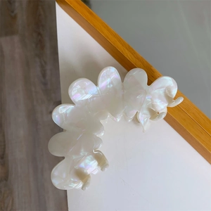 Close-up of large iridescent acetate claw clip with wave edges and pearlescent finish
