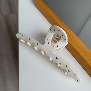 Détail de la pince à cheveux crème en acétate avec strass colorés et ressort métallique