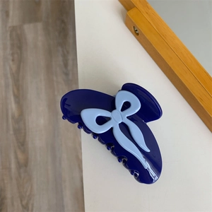 Détail d'une pince à cheveux bleu marine robuste avec un nœud bleu clair au style Y2K
