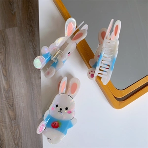 Detail of cute white acetate rabbit hair claw clips with blue shirts and strawberry patterns