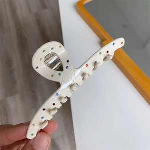 Détail d'une pince à cheveux crème en acétate avec strass colorés et dents solides