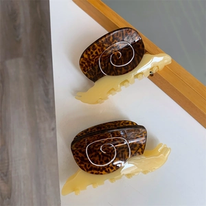 Detailed macro view of two snail-shaped acetate hair claws with leopard shell texture
