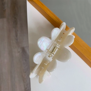 Close-up of iridescent cream acetate hair claw clip with elegant petal flower design