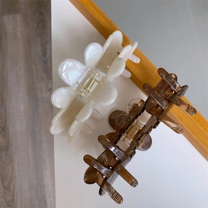 Detailed macro view of acetate flower hair claw clips with pearl and tortoiseshell finish