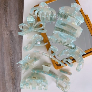 Flat lay of eleven pieces mint green acetate hair claws with marble and pearlescent textures