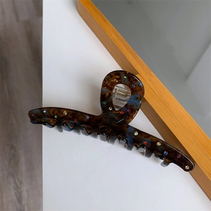 Détail d'une pince à cheveux écaille de tortue avec strass colorés sur une surface blanche