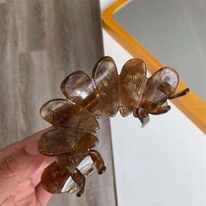 Amber textured acetate flower hair claw clip for women shown in hand with large grip size