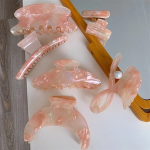 Detailed macro view of pink marble acetate hair claw clips with elegant pearl decoration