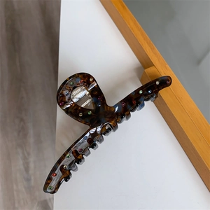 Détail de la pince à cheveux écaille de tortue avec strass colorés sur bureau blanc
