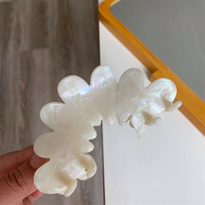 Detailed view of a large pearlescent white acetate hair claw clip with iridescent finish