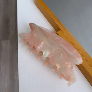 Close-up of a pink marble acetate hair claw clip with a pearlescent finish