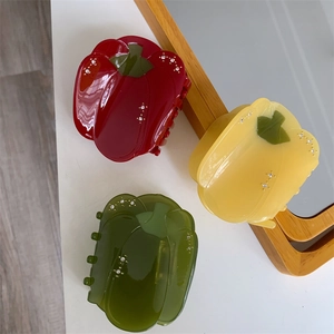 Détail des pinces à cheveux en acétate en forme de poivron avec strass rouges, jaunes et verts
