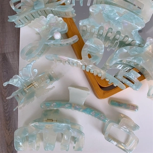 Detailed macro view of mint green acetate hair claws in butterfly and shell shapes