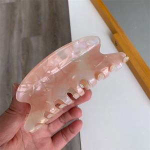 Detailed macro shot of large pink marble acetate hair claw clip with pearlescent finish