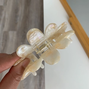 Detail showing high-quality pearlescent cream flower hair claw clip with gold spring