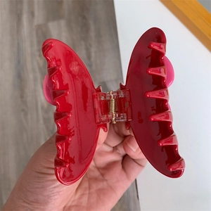 Détail d'une pince à cheveux papillon rouge avec finition brillante et ressort métallique